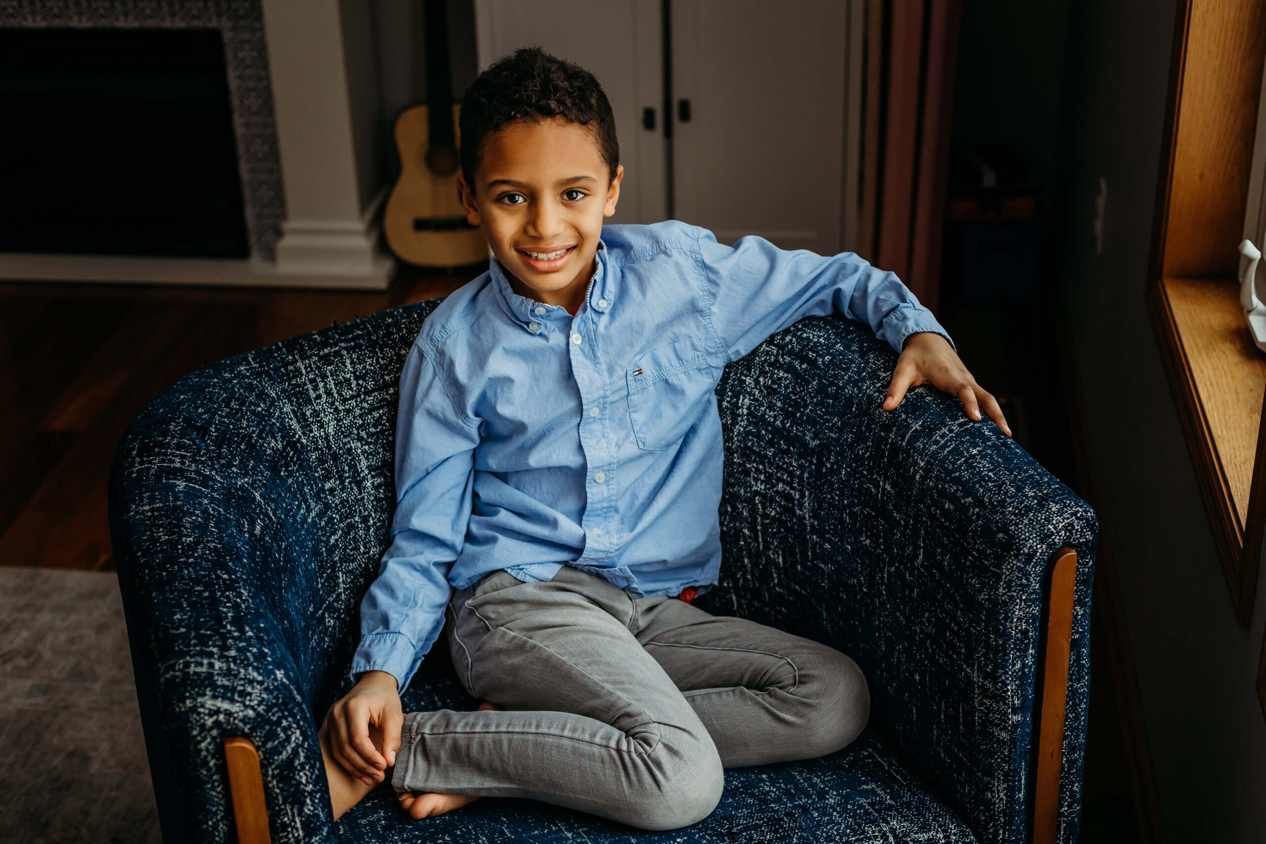 young boy in blue outfit sitting on a couch smiling Once Upon a Child Eau Claire