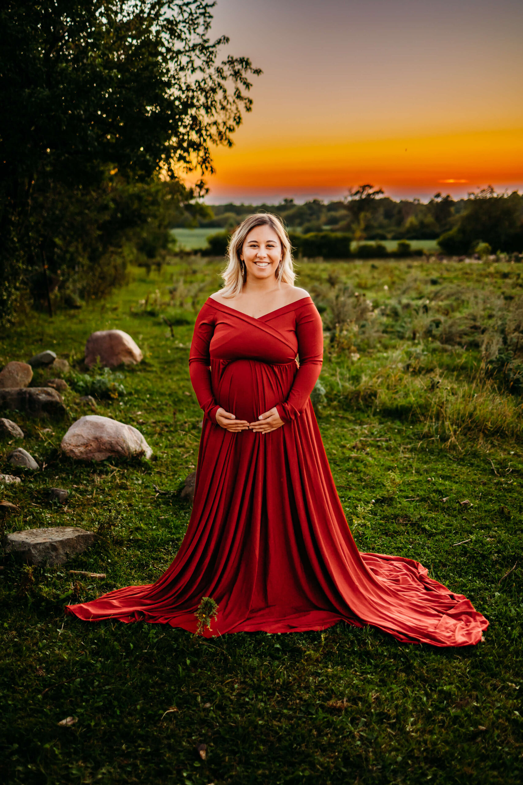pregnant woman in red dress cradling her bump